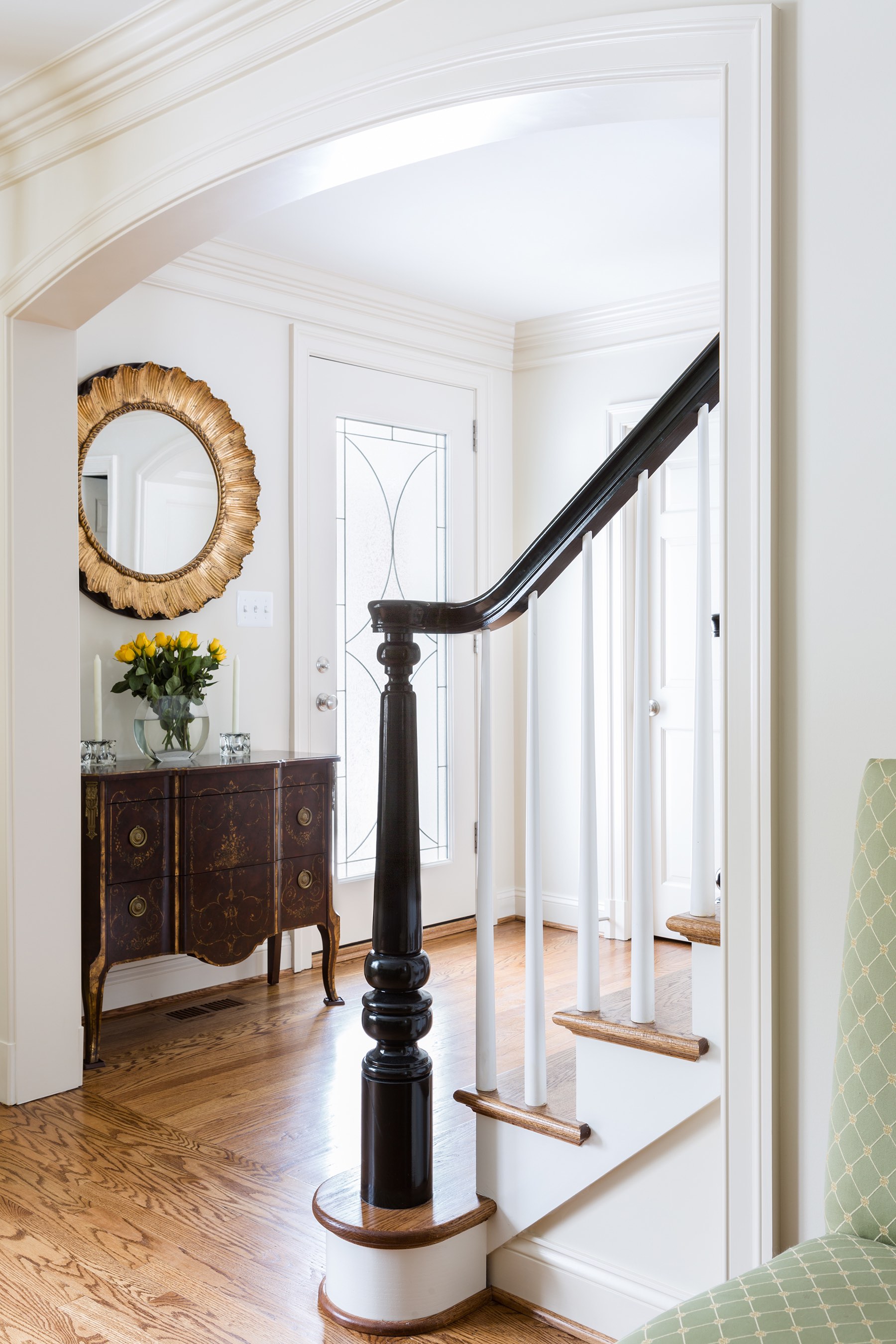 Home grand foyer with antiqued gold mirror and carved black stair newel post