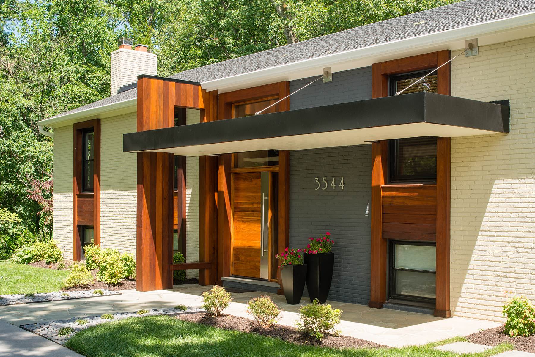 Contemporary home exterior with striking hanging portico and sculptural ipé wood