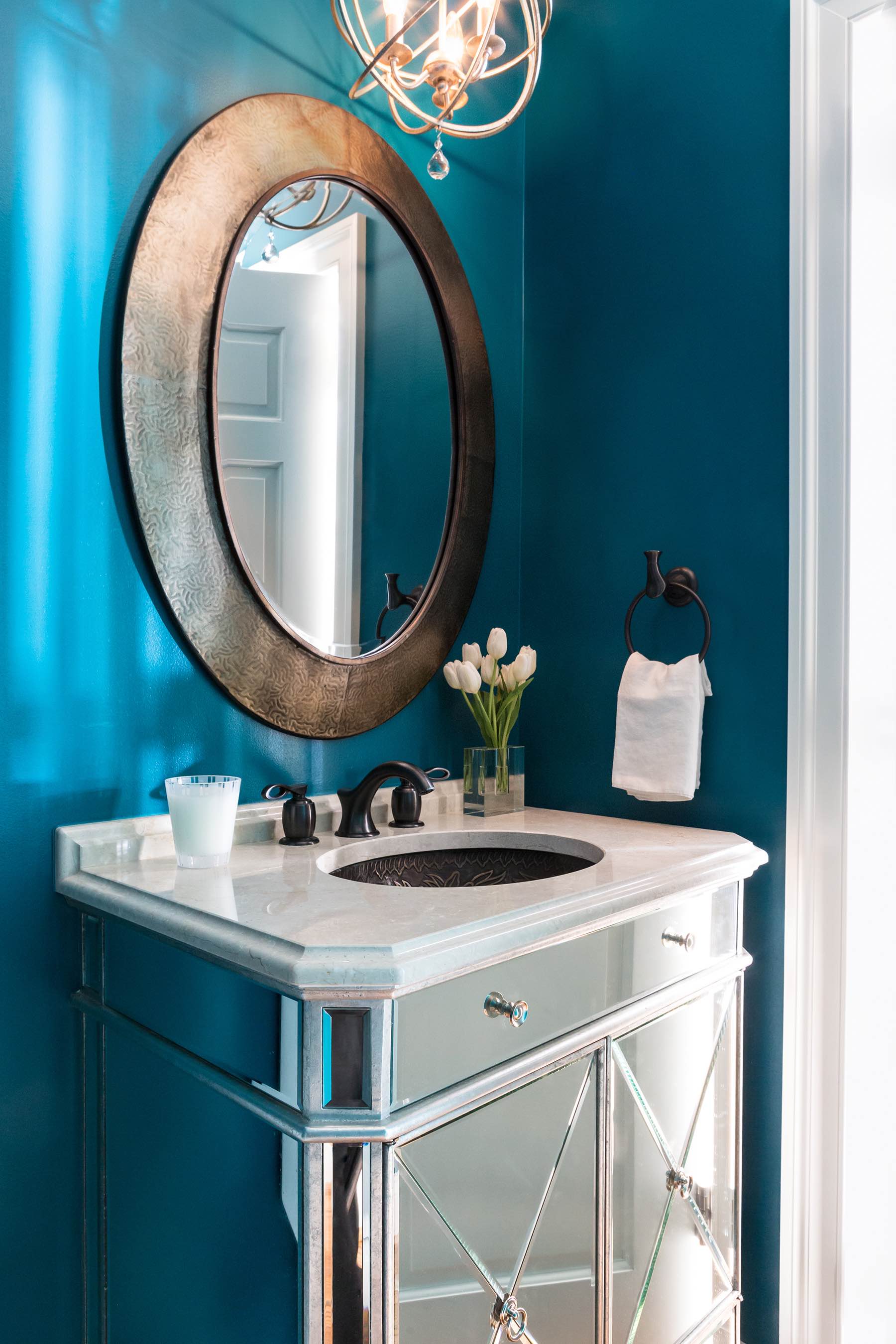 Powder room vanity with mirrored cabinets, teal high-gloss paint, marble vanity top, antiqued gold porthole mirror