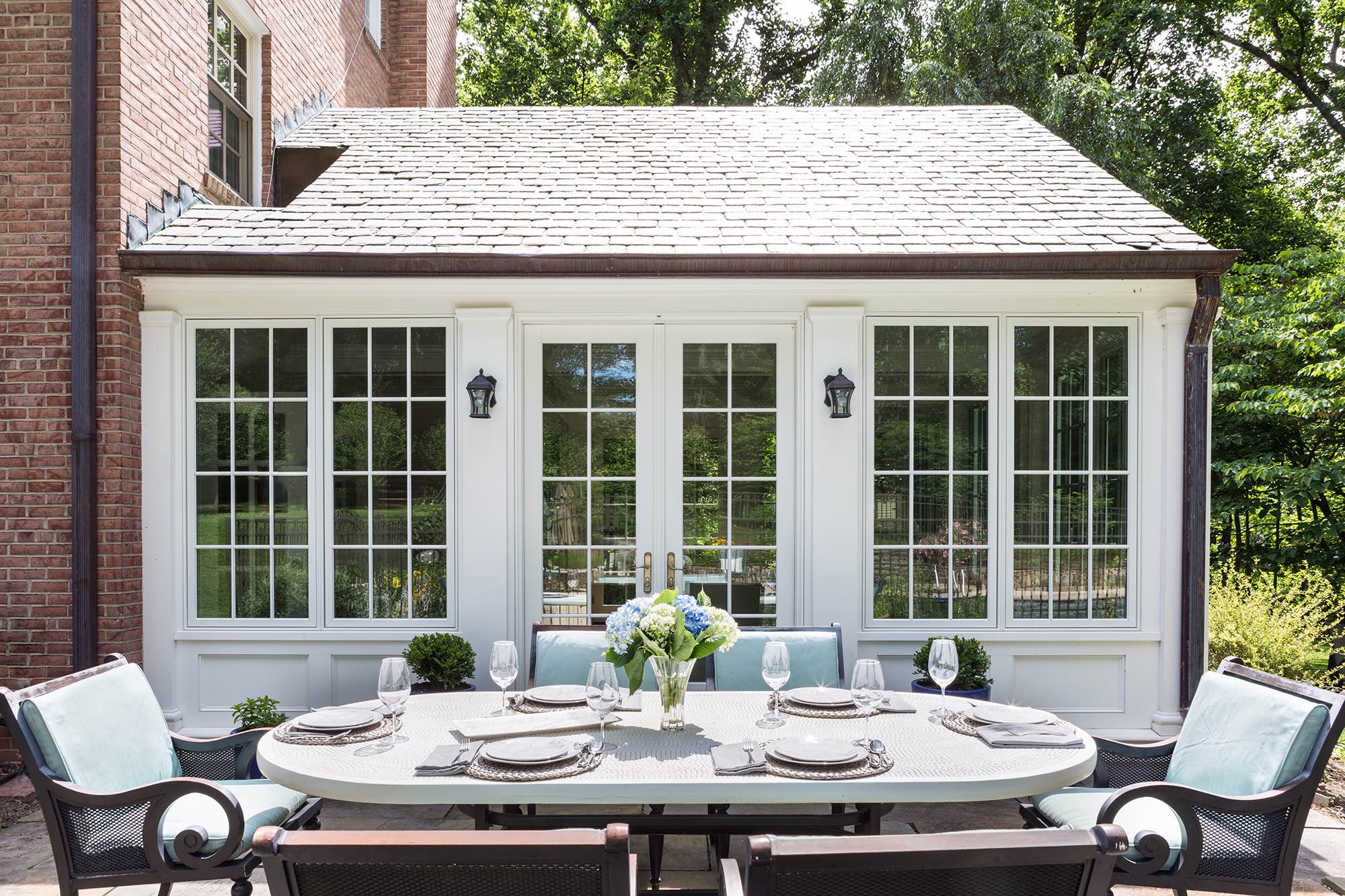 Dining table with bronze and celadon outdoor seating on sunny brick patio