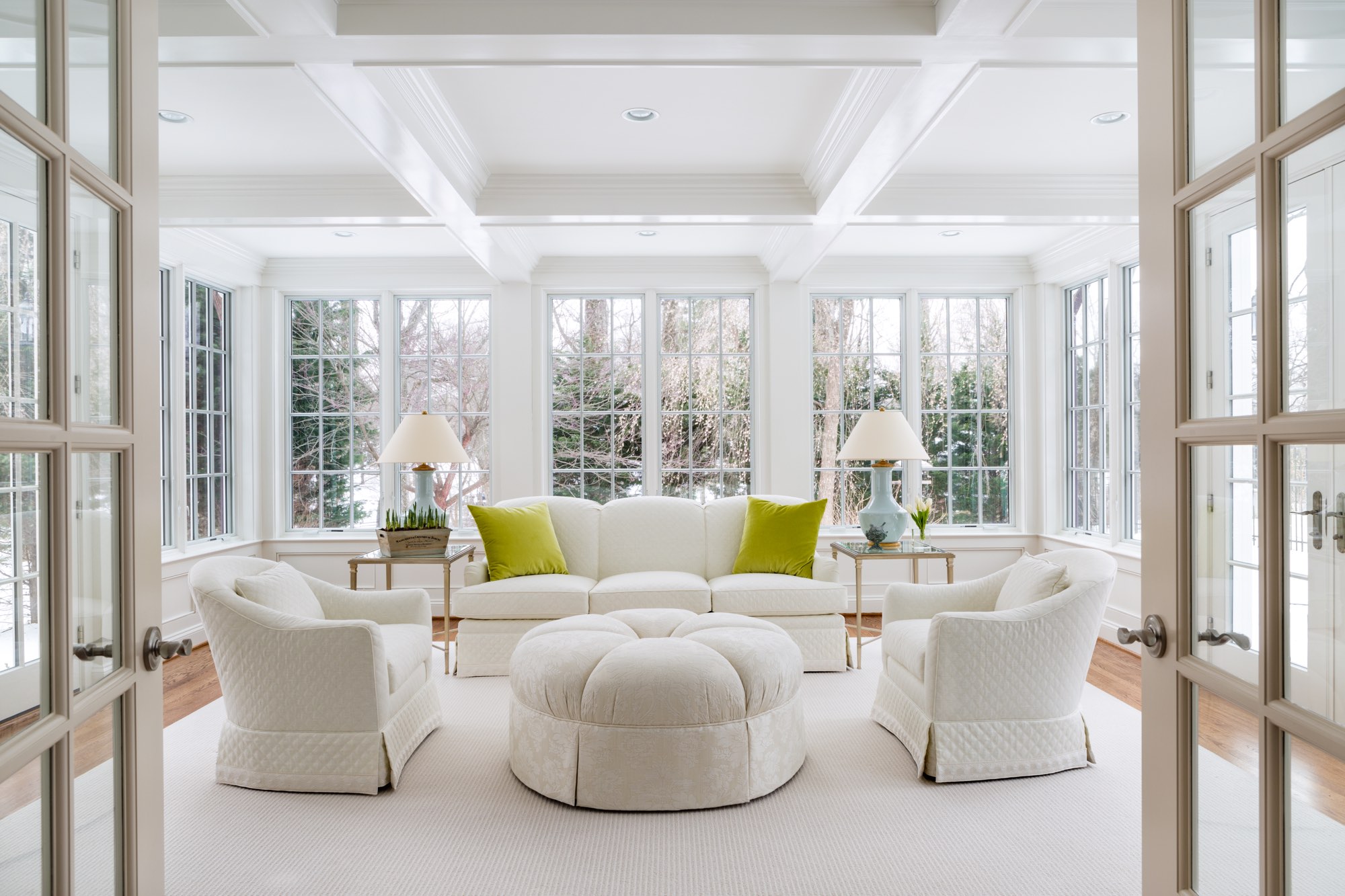Home sunroom renovation with soffit ceiling, white furniture, white windowpanes and view of snowy landscape