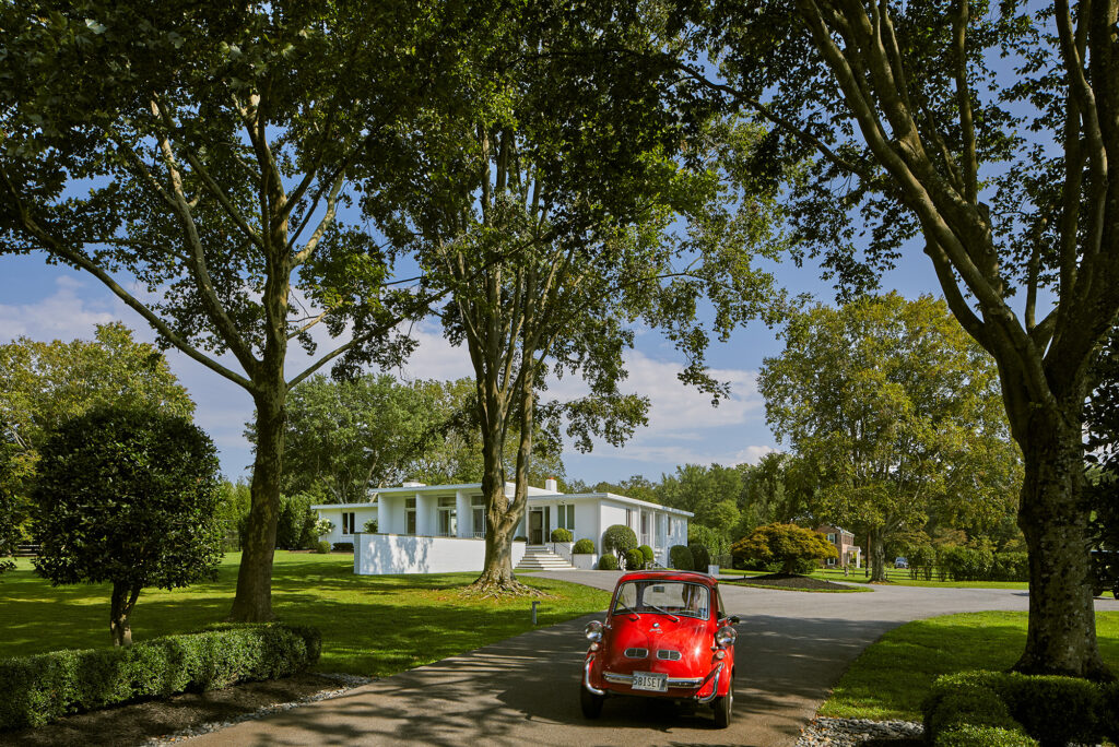 Midcentury modern house with red British car in driveway